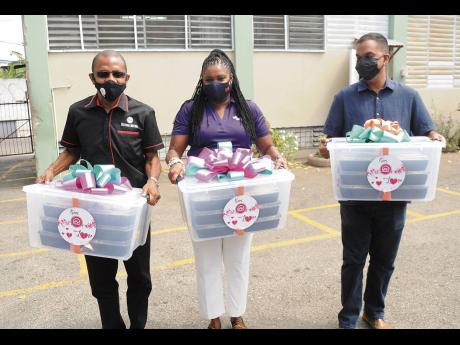  From left: Courtney Campbell, group president and CEO, Victoria Mutual; Clover Moore, assistant vice-president, group corporate affairs and communications; and Robert Lalah, assistant manager, group corporate affairs and communications, carry containers w