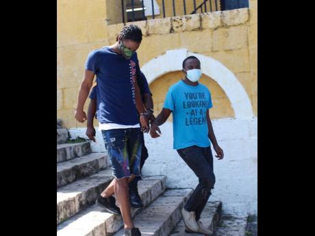 Javan Garwood (right), who is on murder and conspiracy charges in relation to the January fatal church shooting of his stepmother, Andrea Lowe-Garwood, is ushered from the Trelawny Parish Court alongside co-accused Dwight Bingham on Monday. They have been 