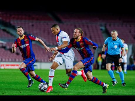 PSG’s Kylian Mbappe (centre) fights for the ball with Barcelona’s Oscar Mingueza (right) during the Champions League round of 16, first-leg match between FC Barcelona and Paris Saint-Germain at the Camp Nou stadium in Barcelona, Spain, yesterday. PSG w