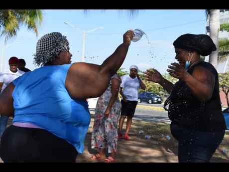 Minister Dionne Harvey (left) anoints a worshipper with water during yesterday’s Ash Wednesday services by the Kingston waterfront.