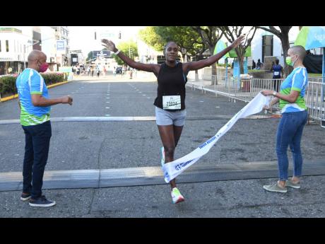 Jozanne Harris crosses the line to win the women’s 5.5K race at the Sagicor SIGMA Corporate Run on the streets of New Kingston, St Andrew, yesterday.
