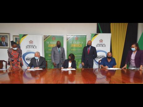 Justice Minister Delroy Chuck (second left) signs a copy of the contract to commence work on the St Ann Family Court. Also signing are Permanent Secretary, Sancia Bennett Templer (centre) and Managing Director of Contraxx Enterprise Limited Stephen Chung. 
