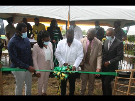Transport Minister Robert Montague (centre) cuts the ribbon to mark the official opening of a new firehouse and rehabilitated runway at the Negril Aerodrome on Thursday. Looking on are Hanover Western Member of Parliament Tamika Davis (second left) and off