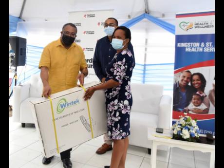 left: Dr Wendy-Ann Byfield Lyons of the Duhaney Park Health Centrer accepts fans from St Andrew Western Member of Parliament Anthony Hylton Health and Welness Minister Dr Christopher Tufton looks on during Thursday’s ceremony.