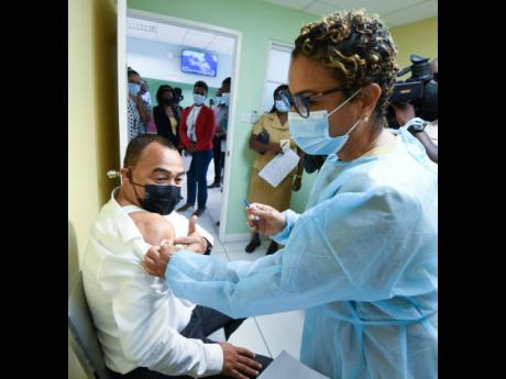 Public Health Nurse Stacy Rennalls applies a plaster to the arm of Heath Minister Dr Christopher Tufton yesterday after simulating the jab process as he toured The Good Samaritan Inn in Kingston, one of 74 sites designated to inoculate Jamaicans from COVID
