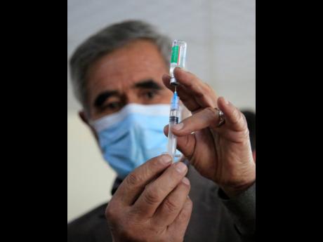 A doctor fills a syringe with the AstraZeneca coronavirus vaccine in Kabul, Afghanistan, on Saturday. Jamaica will receive its first supply this week.