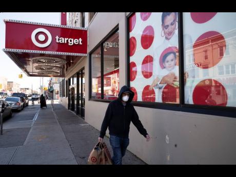 In this April 6, 2020 photo, a customer wearing a mask carries his purchases as he leaves a Target store, in the Brooklyn borough of New York.