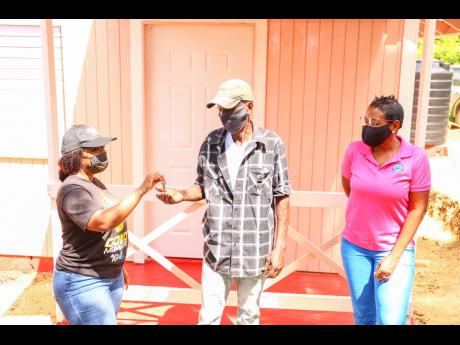 BOOM Brand Manager Keteisha McHugh hands over the keys to a newly built Food For The Poor (FFP) house for 74-year-old Bogle Waldeman in Zion Hill, St Mary, on February 23. Looking on is FFP Development and Marketing Manager Marsha Burrell-Rose. The retired