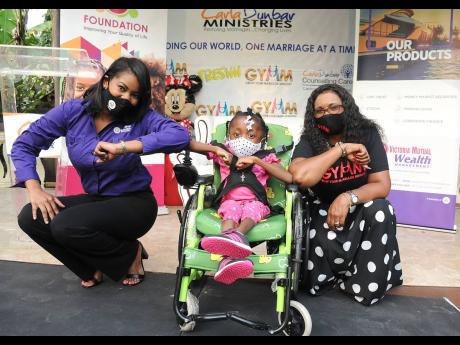 Suzannie Chambers (left), assistant manager, treasury, Victoria Mutual (VM) Wealth Management Ltd, and Carla Dunbar (right) of the Carla Dunbar Ministries, share a photo opportunity with seven-year-old Dominique White, following the recent VM Foundation do
