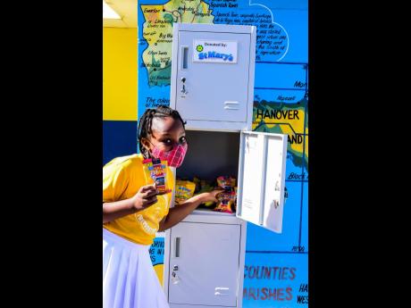 Portmore Missionary Preparatory grade five student Courtney Dawson grabs a JP St Mary’s Extra Crunchy Banana Chips from the lockers donated by JP St Mary’s. Three four-door lockers were handed over last month as part of the company’s overall thrust t