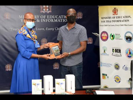 Minister of Education, Youth and Information Fayval Williams (left) receives a tablet from director of the Building Alternative Bridges for Success Foundation, Adrian Reynolds. Occasion was a ceremony for the handover of $500,000 worth of supplies in suppo