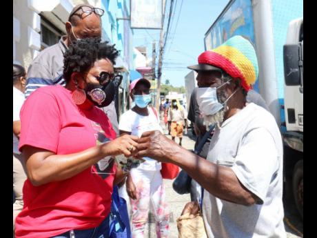 Montego Bay Chamber and Industry President Janet Silvera goes through a COVID-19 information pamphlet with a pedestrian along St James Street in Montego Bay yesterday.