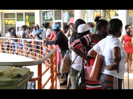 In this April, 2020 photo, long lines are seen in Pavilion Mall, Half-Way Tree, as people waited to collect their compassionate care grant paid out by the Government from a Western Union branch. A year on, Jamaica is grappling with increasing number of COV
