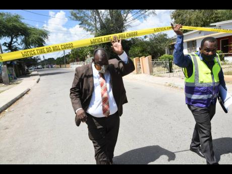 Independent Commission of Investigations’ Nigel Morgan (left), director of complaints, Eastern Region, and Clive Robinson, senior investigator, approach the murder scene where Kenrick Genas who was fatally shot in Sydenham Park, St Catherine, on Thursday