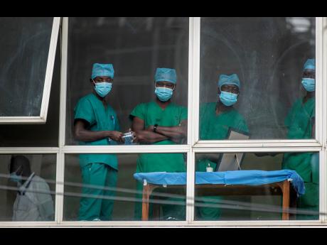 Medical staff look out from a window as officials prepare for a ceremony to commence the country’s first coronavirus vaccinations using AstraZeneca COVID-19 vaccine manufactured by the Serum Institute of India and provided through the global COVAX initia