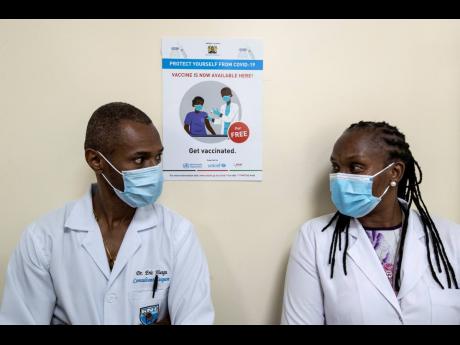 Consultant surgeon Dr. Eric Hungu, left, and Senior Lecturer Dr. Marybeth Maritim, right, wait in line to receive some of the country’s first coronavirus vaccinations using AstraZeneca COVID-19 vaccine manufactured by the Serum Institute of India and pro