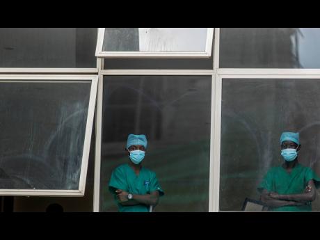 Medical staff look out from a window as officials prepare for a ceremony to commence the country's first coronavirus vaccinations using AstraZeneca COVID-19 vaccine manufactured by the Serum Institute of India and provided through the global COVAX initiati