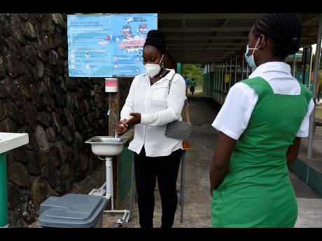 
A student of The Morant Bay High School stands six feet in line from Marsha Ford-Bryan, acting principal, as she washed her hands on February 5, 2021.