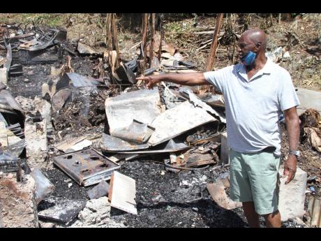 Easton Sharpe, 73 years old, of Commissary district, Frankfield, points to a burnt-out stove from his restaurant which he had been operating for 18 years. 