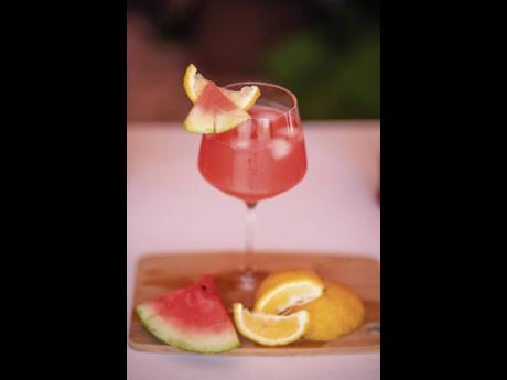 The Red Stripe Watermelon Spritzer, served with watermelon and lemon wedges.