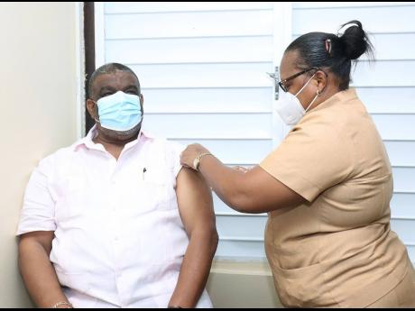 Errol Greene, regional director of the Western Regional Health Authority, leads the way in taking the COVID jab in western Jamaica. Here he is being vaccinated by Angella Stennett-Douglas. 