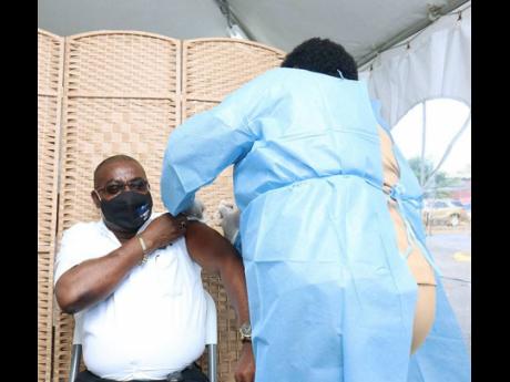 Lennox Wallace, parish manager, Western Regional Health Authority, being vaccinated by Claudette Trought-Gordon.