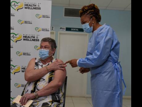 Dr Denise Eldemire-Shearer, professor of public health and ageing at The University of the West Indies, affixes a Band-Aid to her arm after receiving the COVID-19 vaccine from Fiona Ellis, public-health nurse, at the Good Samaritan Inn on Wednesday. Elderm