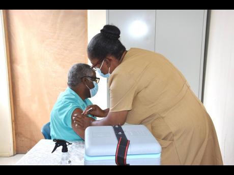 Public Health Nurse Maxine Isaacs administering a shot of the AstraZeneca COVID-19 vaccine to Senior Medical Officer Dr Everton McIntosh at the Mandeville Regional Hospital in Manchester on Wednesday.