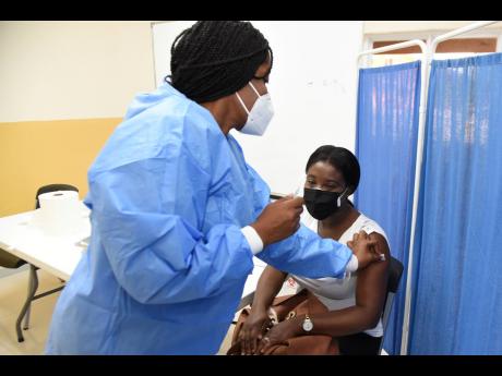 A public health nurse prepares to administer the AstraZeneca vaccine to Registered Nurse Shauna Callum-Lindsay at the University Hospital of the West Indies in St Andrew yesterday. Callum-Lindsay said the virus had caused her to be fearful working while pr