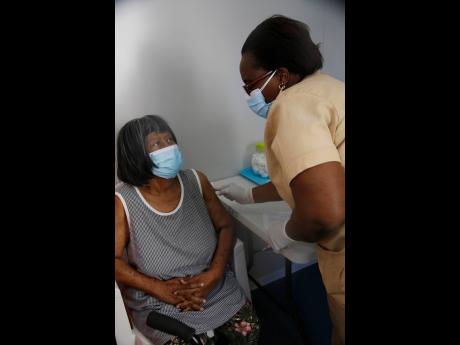 Public health nurse Ann-Marie Menzie administers the COVID-19 vaccine to Herman Bryant-Manning, an 81-year-old retired nurse, at the May Pen Hospital vaccination centre in Clarendon yesterday. Bryant-Manning, a nurse for 50 years, says she has never seen a