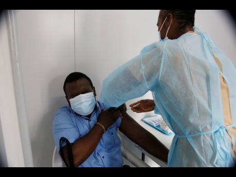 
May Pen Hospital pharmacist Chad Clarke winces as he gets his first dose of the COVID-19 vaccine from a public health nurse last Wednesday. Clarke told The Sunday Gleaner that he took the jab mainly to protect his family as he could take home the virus be