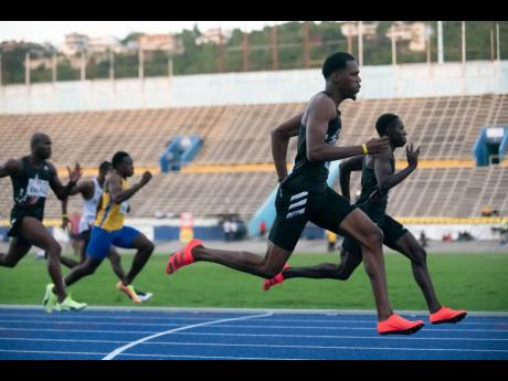 Zharnel Hughes (foreground) wins the men's 100m event at the JAAA Qualification Trials 3.6 held at he National Stadium yesterday, in a time of 10.13 seconds. Oblique Seville (background), was second in 10.18 seconds.