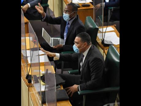 Prime Minister Andrew Holness (foreground) leads the banging of desks on the government benches while jeering Opposition Leader Mark Golding during his Budget Debate presentation on Tuesday. 