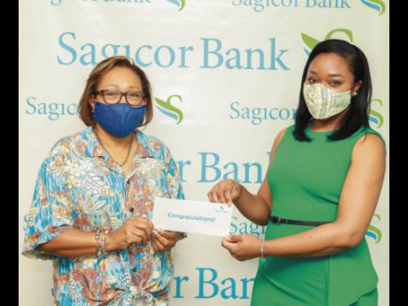 Terry-Ann Heffes (left), Sagicor Bank Jamaica client and one of three winners of the financial institution’s recent credit card promotion, is presented with her hotel voucher for the all-expense paid three-night stay at Secrets Wild Orchid Resort in Mont