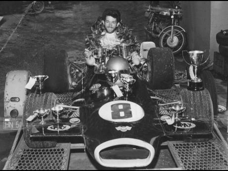 In this November 1974 photo, Peter Moodie, then 20 years old, is seen garlanded and surrounded by trophies in his Brabham Ford race car.