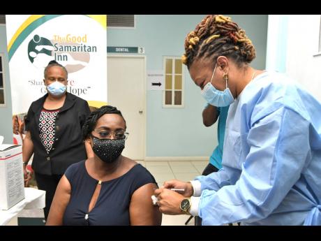 Juliet Holness, member of parliament for St Andrew East Rural and wife of Prime Minister Andrew Holness, gets her COVID-19 shot from public health nurse Fiona Ellis at the Good Samaritan Inn on Monday.