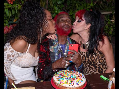 It’s a ‘Scratch sandwich’ as friend Marcia Reid (left) and wife Mireille Perry shower Lee ‘Scratch’ Perry with kisses on his birthday. 