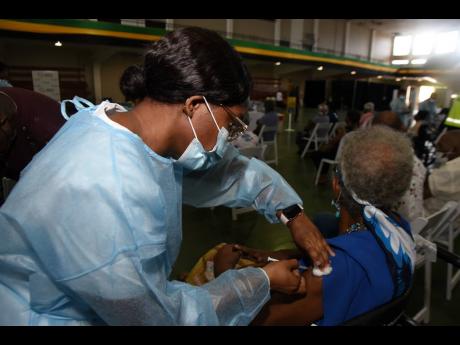 A senior citizen is inoculated with a dose of Oxford-AstraZeneca by a public health nurse during a vaccination blitz for persons 75 years and older at the National Arena on Saturday.