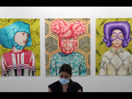 A gallery employee works in front of Angeles Agrela paintings at the 14th edition of Art Dubai at Dubai International Financial Centre, DIFC.