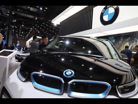 
In this April 17, 2019 photo, a worker cleans an electric vehicle at the BMW booth during the Auto Shanghai 2019 show in China.