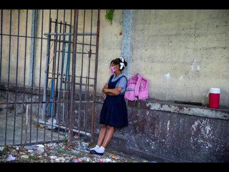 In this August 17, 2020 photo, a student waits for her turn to enter the Lycee Marie Jeanne school on the first day back  since the COVID-19 pandemic in Port-au-Prince, Haiti.