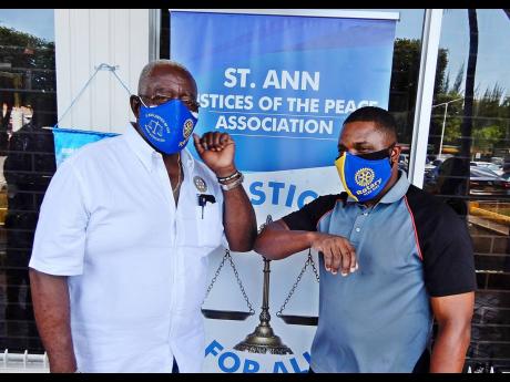 Rodney Campbell (right), shows his appreciation at getting a mask by touching elbows with Pixley Irons, JP and president of the Rotary Club of Ocho Rios.  