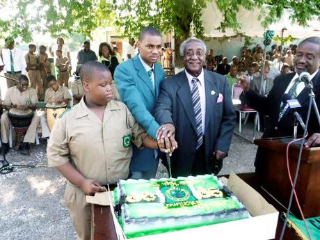 The Rev Dr Horace Russell cuts a cake alongside Olympian Warren Weir (centre) at Calabar High School while the Rev Dr Karl Johnson, general secretary of the Jamaica Baptist Union, looks on. Russell died on Monday aged 91.