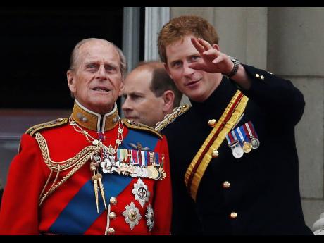 Britain's Prince Harry talks to Prince Philip as members of the Royal family appear on the balcony of Buckingham Palace, during the Trooping The Colour parade, in central London on June 14, 2014. Buckingham Palace officials say Prince Philip, the husband o