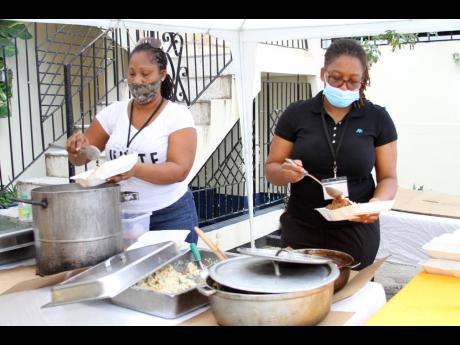 Volunteers, Shellie Farquharson (left) and Jennel Rodney of Kingdom Embassy Family Ministry International pack cooked meals for Judah Company of Prophets International Ministries initiative to feed less fortunate and needy people.
