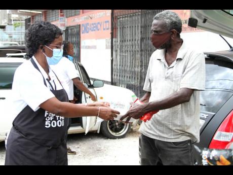 Debbie-Ann Hibbert, minister with Judah Company of Prophets International Ministries, hands a package with cooked meal to a resident of May Pen.  The Denbigh, Clarendon-based non-profit organisation hosts a quarterly feeding initiative, “Feeding of the 5