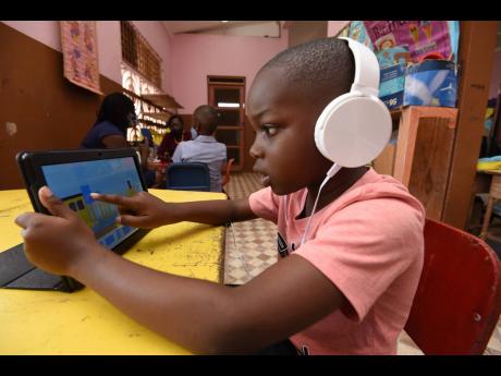 Seven-year-old Joachim Walker works on his tablet computer. A student of Kitson Town Primary School in St Catherine was one of the recipients of the tablet computers. 
