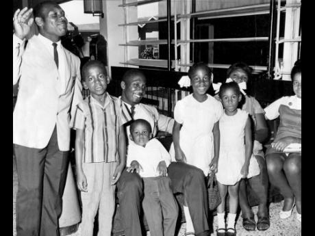 Weightlifter Cedric Demetrius (left) and fellow weightlifter Keith Bailey (sitting third from left) pose with members of their families ahead of their departure to the 1968 Olympic Games in Mexico City, Mexico. 