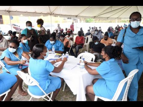 Health workers and hundreds of anxious people awaiting the arrival of the COVID-19 jabs at the Old Harbour Civic Centre in St Catherine on Tuesday. The vaccines arrived in the afternoon, hours after the scheduled 9 a.m. start.