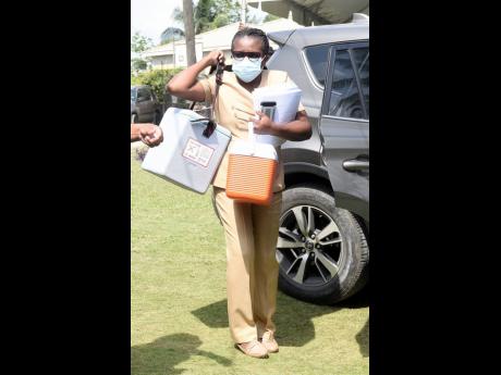 Public health nurse Novlette Stennett arriving at the Holy Trinity Anglican Church in Linstead, St Catherine, with an igloo with roughly  200 COVID-19 doses on Tuesday. The centre ran out of vaccines early in the morning, with some persons waiting more tha